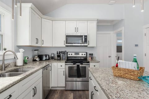 Modern kitchen w/ stainless appliances, white cabinetry & island prep space