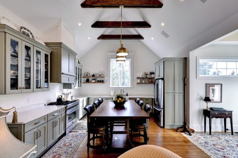 Vaulted-beam chef’s kitchen with island table, quartz, and stainless.