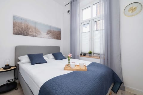 Cozy bedroom with a double bed, soft lighting and bright windows.