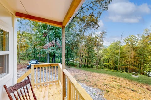 Covered front porch with rocking chair and sweeping forest & mountain views. Private tiny cabin retreat, peaceful countryside getaway, perfect for couples, remote work, nature lovers.