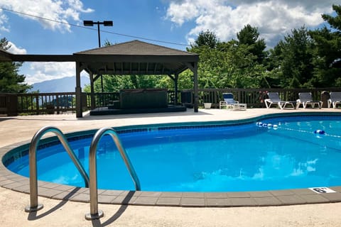 Seasonal community swimming pool with spacious deck, loungers, and shaded pavilion. Perfect for cooling off during summer vacations.