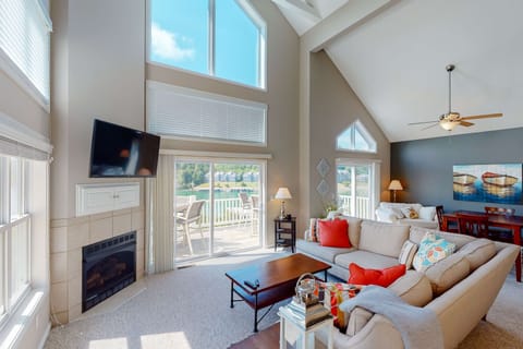Sun-filled living room with soaring ceilings, gas fireplace, and direct access to the deck. Perfect for relaxing with lake views year-round.