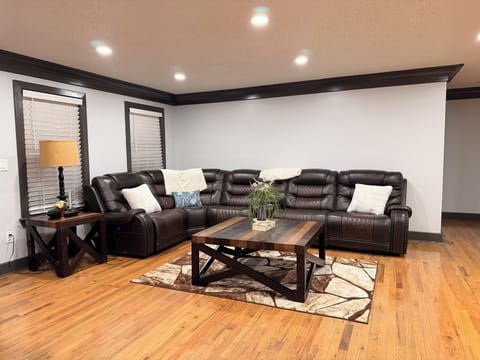 Living room with a reclining couch, extra seating, high-top table, & Smart TV.