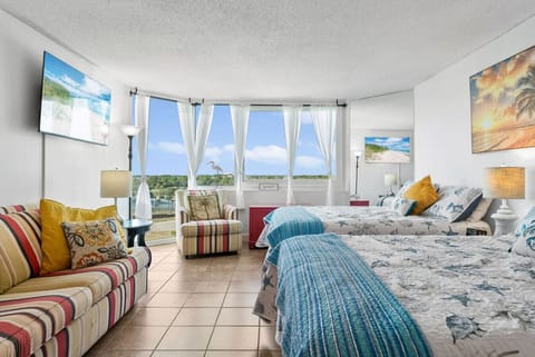 Bright studio with two comfy beds, cozy seating, and floor-to-ceiling windows