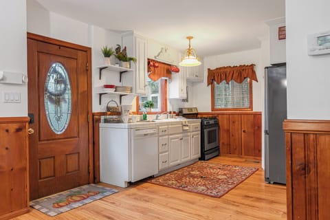 Kitchen with white cabinets, light wood trim, a stainless steel sink, and a patterned rug.
