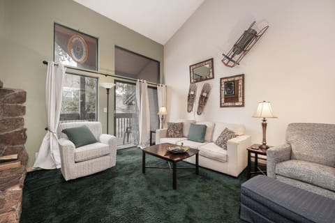 Unwind in your cozy living space with vaulted ceilings, comfortable seating, and charming vintage ski decor that creates the perfect mountain retreat atmosphere.