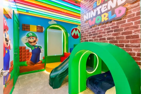 Discover a vibrant playroom filled with colorful murals of beloved characters and glowing ceiling lights. The bright green slide and cozy nook create a fun and relaxing space where kids can enjoy themselves.