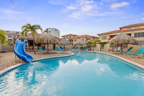 Community pool with slide, sun beds and palapas