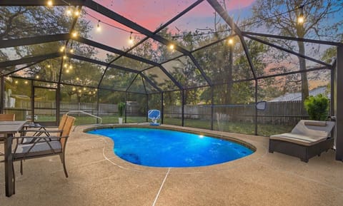 Spacious screened-in pool with dining table and lounge seating.