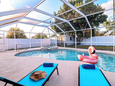 Dive into your private screened pool—sun, shade, and pink flamingo floats await.
