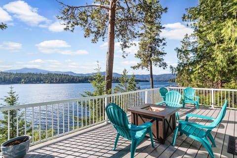 Bright upper deck with Adirondack chairs, fire pit table, and sweeping lake-and-mountain view — the shot that makes you book