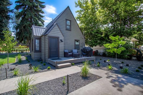 Bright exterior - A-frame cottage with metal roof, back deck seating, and covered gas grill tucked into mature trees
