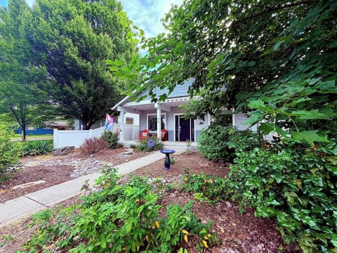 Sunny craftsman exterior with covered front porch, lush landscaping, and white vinyl fence — a welcoming first impression every arrival