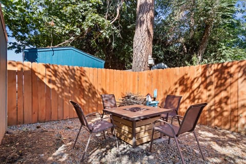 Sunny fenced backyard with square gas firepit table and seating for four under mature trees — your evening hangout sorted