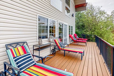 Spacious balcony ideal for relaxing, gathering with friends, and enjoying the view. Outfitted with loungers, comfortable seating, a propane BBQ, a fire pit, and a table with chairs for outdoor dining.