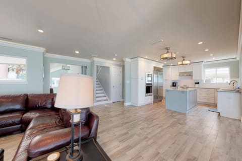 Bright coastal open-concept living with a designer kitchen, island seating, and comfy leather lounge. Perfect for relaxing after a day at the beach during your unforgettable beach stay.