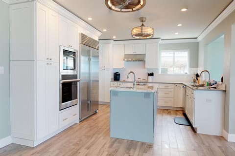 Stylish, fully equipped coastal kitchen with stainless steel appliances, spacious island, and beach-inspired design. Perfect for preparing meals and gathering together during a relaxed and memorable beach stay.