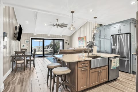Experience open-concept coastal living with a spacious kitchen, dining, and living area flowing to ocean-view doors. Perfect for a beach stay, this inviting space blends modern comfort with relaxed seaside style.