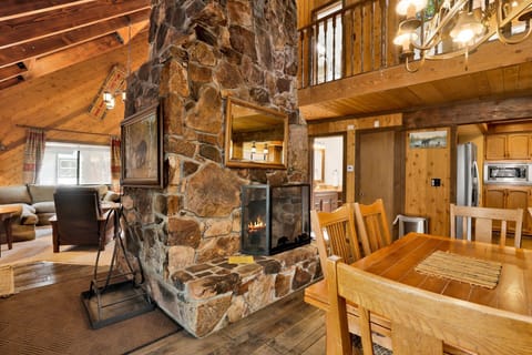 Cozy cabin living room with a stone fireplace, comfy seating, and a TV—perfect for relaxing evenings, movie nights, and unforgettable mountain getaways.