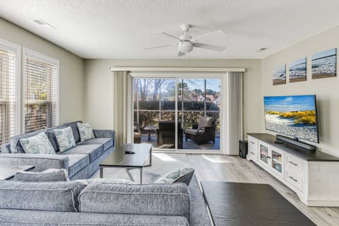 Relax in the living room with a spacious sofa, a large flat-screen TV, and direct access to the screened porch.