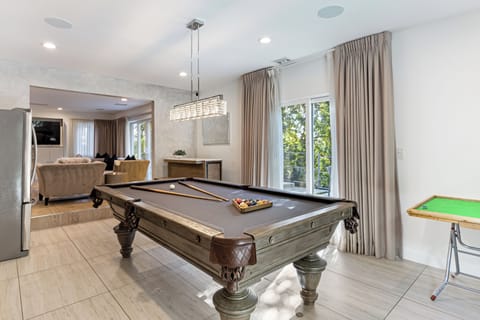 Indoor recreation room with a pool table and large windows.