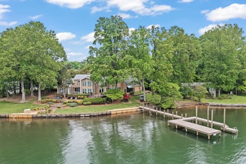 Expansive lakeside estate framed by mature trees, sprawling decks, and a private dock stretching over calm Lake Norman waters.