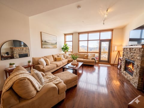 Open plan living room with natural gas fireplace, BBQ deck, comfy seating and stunning views of The Rockies.