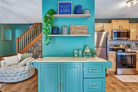 With its bold lake-inspired accents, cozy swivel chairs, and a stone fireplace at the center, this inviting space seamlessly connects relaxation, style, and easy access to the kitchen—perfect for laid-back gatherings and warm conversation.
