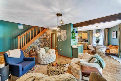 Main Floor Living Room: Gather around the stunning stone fireplace in this cozy yet stylish space that connects effortlessly to the kitchen and dining area—complete with bold wallpaper and thoughtfully curated design.