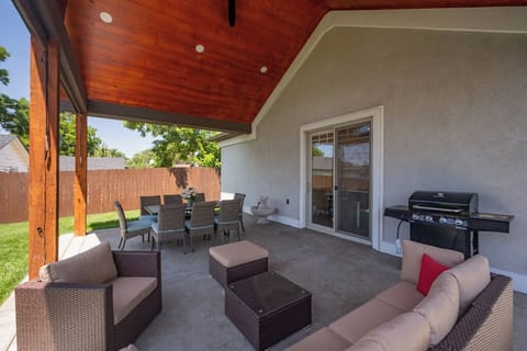 Large covered patio with seating, firepit, grill and table