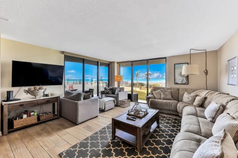 Bright beachfront living room featuring panoramic ocean views, plush seating, and floor-to-ceiling windows. Relax in coastal comfort just steps from the beach—perfect for your next seaside vacation stay.