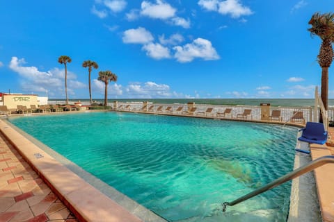 Relax at this sparkling beach-stay pool overlooking the ocean, featuring plenty of loungers and space to soak up the sun—perfect for enjoying the coastal breeze and shoreline scenery.