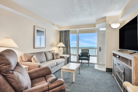 Bright oceanfront living room with comfy seating, large TV, and direct access to your private balcony. Enjoy relaxing beach stay vibes with stunning shoreline views right from your sofa.
