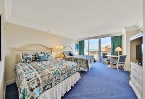 Spacious beach stay bedroom featuring two comfy beds, vibrant coastal décor, and floor-to-ceiling windows showcasing stunning ocean views—perfect for relaxing after a day in the sun and surf.