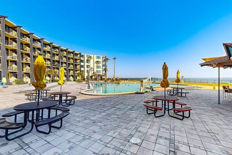 Enjoy your beach stay at this oceanfront pool deck featuring lounge seating, shaded tables, and direct views of the shoreline. Ideal for relaxing, swimming, and soaking up the coastal sunshine just steps from the beach.