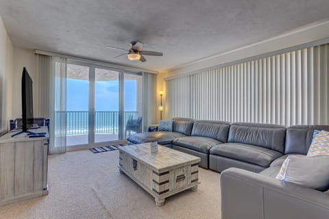 Bright oceanfront living room featuring plush seating, coastal décor, and sliding glass doors to a private balcony. Enjoy relaxing beach stays with stunning ocean views, sea breezes, and easy access to sand and surf.