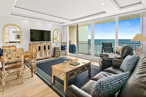 Relax in this bright oceanfront living space featuring comfortable seating, coastal décor, and floor-to-ceiling windows. Step onto the private balcony and enjoy breathtaking beach views—perfect for an unforgettable seaside vacation stay.