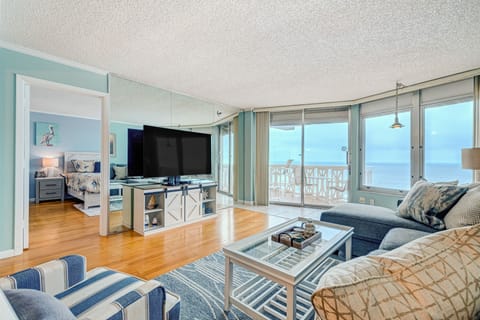 Bright oceanfront living room featuring floor-to-ceiling windows, coastal décor, and private balcony access. Relax in comfort while enjoying sweeping beach views—perfect for an unforgettable seaside vacation stay.