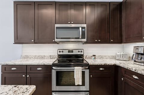 Stylish kitchen cooking space with stainless steel range, microwave, and granite countertops. Designed for easy meal prep so you can spend less time cooking and more time enjoying your beach stay vacation.