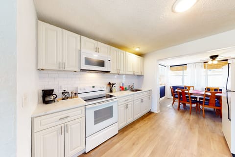 Enjoy home-cooked meals in this bright beach stay kitchen featuring white cabinetry, full-size appliances, and ample counter space. Open to the dining area, it's perfect for gathering after a relaxing day at the beach.