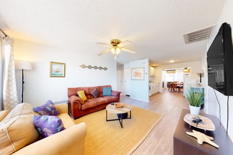 Enjoy this bright, open-concept beach stay featuring a cozy living area, smart TV, and seamless flow into the kitchen and dining space. Perfect for relaxing and gathering after a sun-filled day at the beach on your coastal getaway.