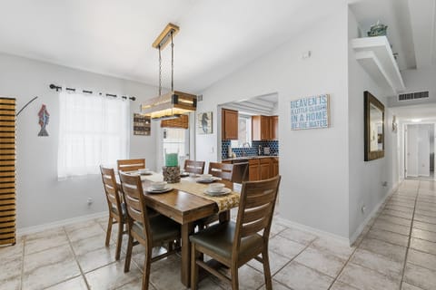 Share meals during your beach stay in this inviting coastal dining area with warm wood furnishings, beach-inspired accents, and easy access to the kitchen—perfect for family dinners and planning your next day at the beach.