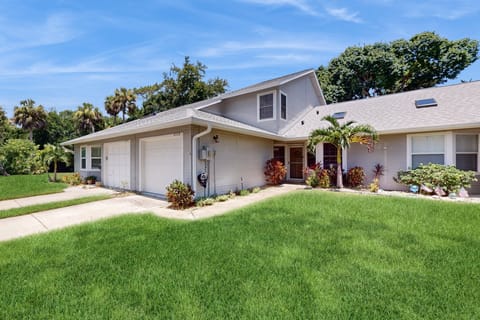 Bright, welcoming front exterior of this beachside villa featuring lush landscaping and a private garage—your perfect starting point for a relaxing beach stay.