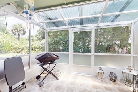 Relax on this peaceful screened patio surrounded by lush greenery. Enjoy a quiet beach stay retreat with a grill, comfy seating, and plenty of natural light—perfect for unwinding after a day by the shore.