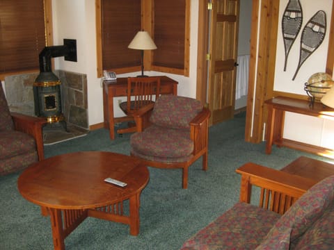 Inside the 3BR home, the cozy living area showcases comfortable furniture and a stylish wood stove, creating a warm atmosphere ideal for relaxation.