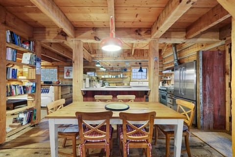 Cozy wooden dining nook with open shelving and warm cabin lighting.