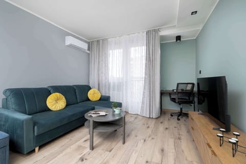 The deep-green sofa creates a cosy relaxation area where natural light from the large window helps you unwind after a busy day.