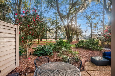 Step onto your private patio where morning sun filters through towering oaks and vibrant camellias create a colorful garden sanctuary.