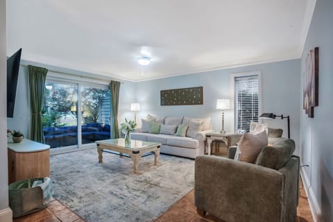 Sink into plush sofas surrounded by soothing blues and greens, where natural light streams through garden views for your perfect relaxation retreat.