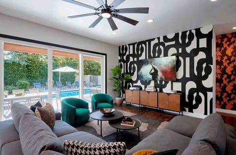 The living room offers a stylish, welcoming space with a roomy sectional, bold accent wall, cozy seating, and a smart TV for easy entertainment.